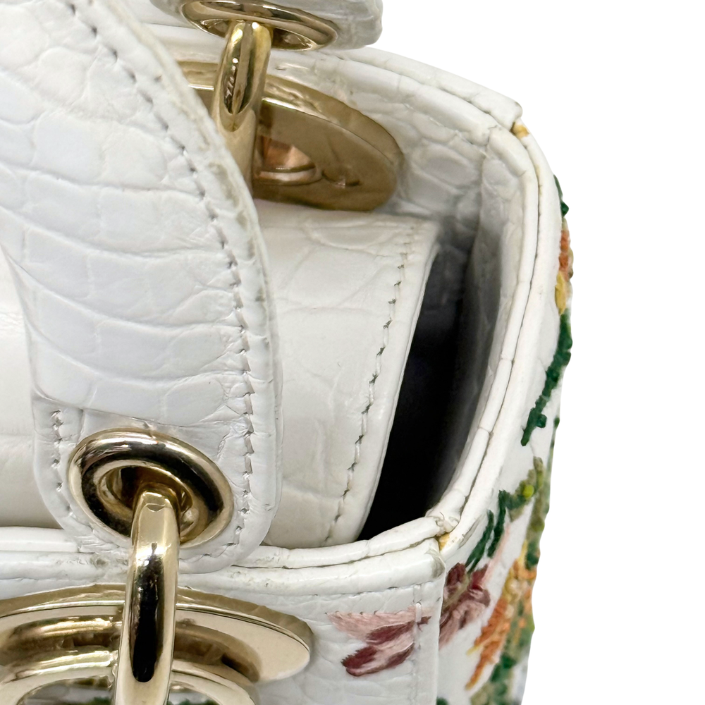White leather mini handbag open showing inner lining and gold ring clasp