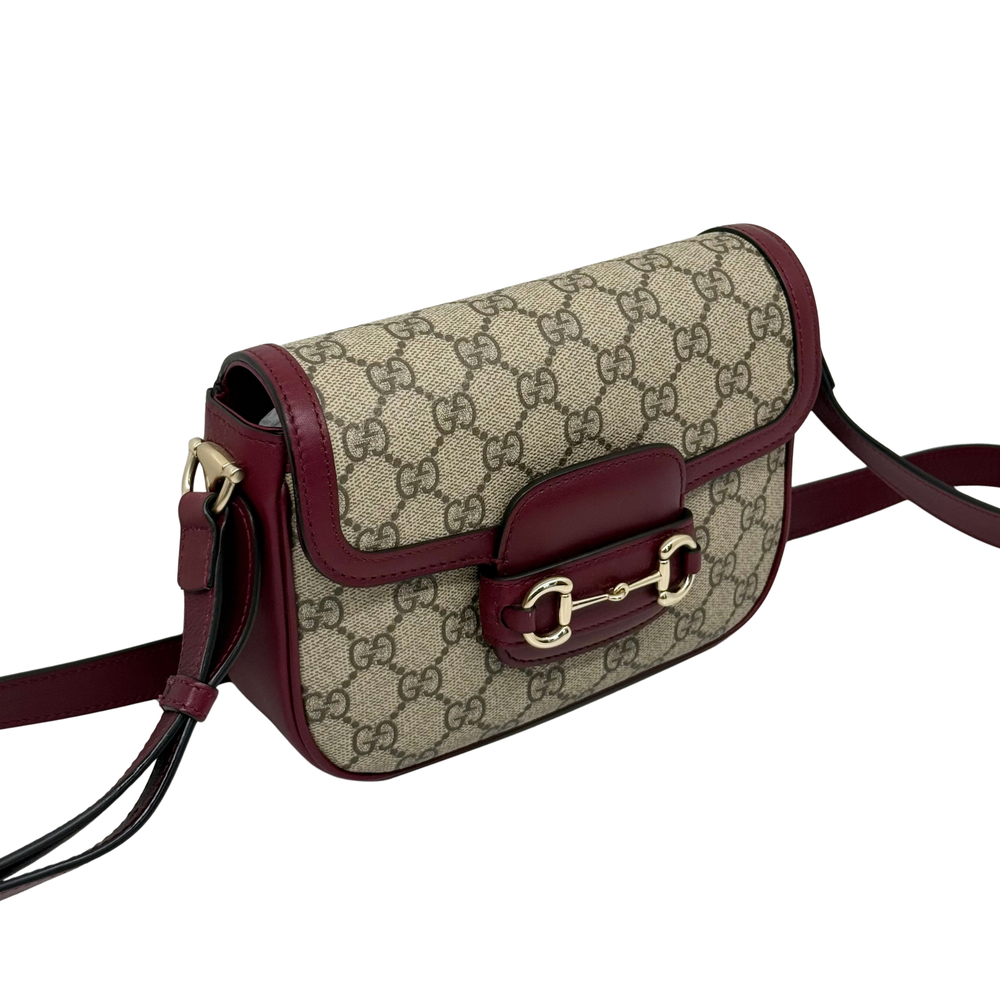 Gucci GG crossbody bag angled view with burgundy flap and gold buckle hardware